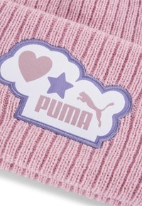 Pletena ružičasta kapa koja ima teksturirani uzorak, bijeli oblačni detalj s ljubičastim naglascima, te riječ "PUMA" u debelom fontu.