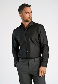 Zwarte lange mouwen shirt met een subtiele textuur, knoopsluiting aan de voorkant en een gespreide kraag, gecombineerd met grijze broeken.