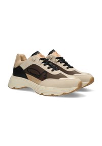 Zapatilla beige y marrón que presenta una mezcla de texturas suaves y de ante, forma redondeada, acento negro y suela de goma con banda de rodadura visible.