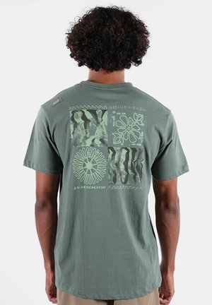 T-shirt en coton vert olive avec un motif graphique au dos présentant divers motifs et textures dans des tons verts doux. Manches courtes.