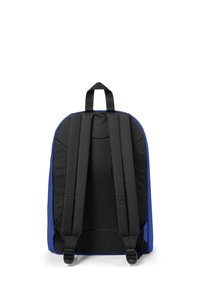Zadní pohled na modro-černý batoh s polstrovanými ramenními popruhy a horní rukojetí. Batoh má hladkou textilii a aerodynamický design.