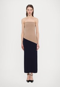 Bežinė bodice ir įstrižinė tamsiai mėlyna sijonas be petnešėlių maksi suknelė; pagaminta iš lygaus, tamprios medžiagos. Batai su čiurnos dirželiu.