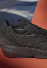 Black athletic shoes featuring a mesh upper, textured accents, and a lightweight soles with "LIGHTSTRIKE" branding.