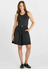 Shorts en jean noir à taille haute, avec poches latérales et coupe décontractée, associés à un débardeur noir. Texture lisse et design simple.