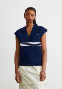 Μπλέ ναυτικού ριπ πλεκτό αμάνικο τοπ με V-λαιμό, που διαθέτει τρεις λευκές οριζόντιες ρίγες στο στήθος και κεντημένο λογότυπο.