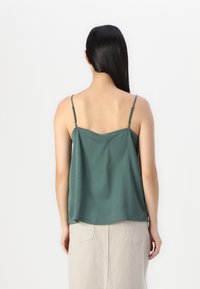 Dark green sleeveless top with adjustable spaghetti straps and a relaxed fit, made from a soft fabric with a smooth texture.