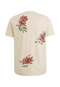 T-shirt crème avec des motifs floraux rouges et verts dans le dos. Manches courtes et coupe décontractée. Matériau en coton doux.