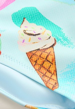Kornet s mäkkou zmrzlinou s posypom, vytlačený na svetlo modrom látkovom podklade s detailmi šitia.