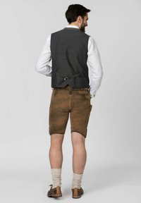 Grahamuster-Weste, braune Lederhosen, cremefarbene Socken und braune Schuhe. Die Weste verfügt über einen Rückenriemen mit einer Schnalle.