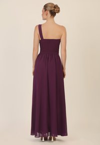 Langes, ärmelloses lila Kleid mit gerafftem Oberteil, fließendem Stoff und einem einzelnen Schulterträger. Elegante und weiche Textur, bis zu den Knöcheln.