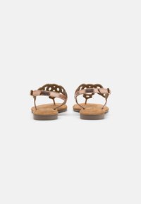 Brown leather sandals with a flat sole, featuring cut-out detailing on the straps and an adjustable ankle buckle for a secure fit.