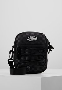 Schwarz-weiß karierter Crossbody-Beutel mit Reißverschluss, elastischen Kordeldetails und einem Vans-Logo. Verfügt über einen abnehmbaren Trageriemen und strukturierte Stoffe.