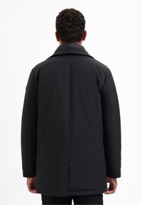 Zwarte, geïsoleerde jas met een opvouwbare kraag, lange mouwen en zijzakken. Glad textuur, slim fit en minimale stikseldetails.