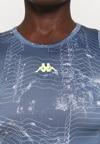 Blue athletic tank top with a sleek design, featuring a white abstract pattern and a yellow logo at the center. Smooth, stretchy fabric.