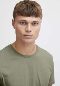 Olive green t-shirt with a crew neckline, made from soft fabric. The shirt has a smooth texture and a standard fit, without patterns or embellishments.