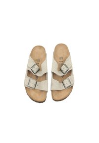 Sandales en daim beige avec deux sangles réglables et boucles en métal argenté. Semelle en liège conçue pour épouser la forme du pied et semelle extérieure en caoutchouc texturé.