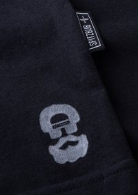 Schwarzes Baumwoll-T-Shirt mit einem hellgrauen Grafikdesign eines Schädels mit Bart. Enthält ein kleines Etikett mit der Aufschrift "SPITZBUB." Glatte Textur.
