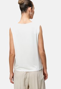 White sleeveless top with a relaxed fit, smooth texture, and round neckline. Back view shows shoulder line and simple design.