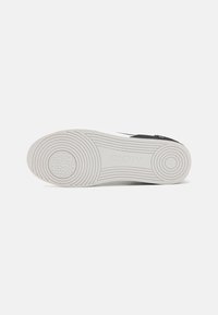 Mustad mustad mustad, valge kummist tald, ümmargune haardepattern ja DKNY logo reljeefselt. Sile tekstuur kaasaegse disainiga. Tasane nöörita stiil.