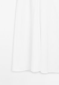 Witte, lange jurk gemaakt van lichtgewicht stof, met een eenvoudig ontwerp en een gladde textuur zonder zichtbare patronen of accenten.