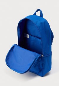 Μπλε υφασμάτινο σακίδιο με κλείσιμο φερμουάρ και ανοιχτή μπροστινή τσέπη. Διαθέτει ομαλή υφή και εσωτερικό χώρο αποθήκευσης.