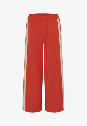 Pantaloni roșii cu croială largă și talie elastică, cu dungi albe pe lateralele picioarelor, confecționați dintr-un material neted.