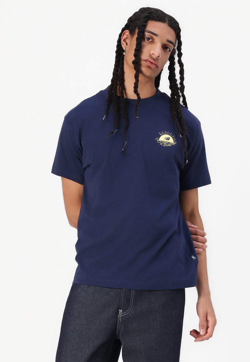 Camiseta de algodón de manga corta en azul marino, con un gráfico de sol amarillo en el pecho. Corte simple y relajado, con cuello redondo.