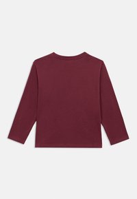 Bordó, hosszú ujjú, kerek nyakú póló, laposan elhelyezve, a hátoldala látható, fehér háttér előtt.