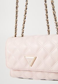Rosa gesteppte Lederhandtasche mit einem goldenen dreieckigen Logo, doppelten Metallkettenträgern und einer glatten Textur. Verfügt über eine kompakte rechteckige Form.