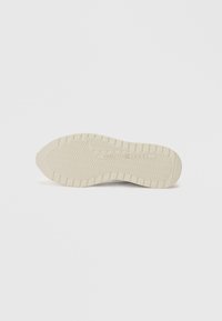 Sole boty v off-white gumě s texturovaným povrchem a cik-cak vzorem, s vyvýšeným logem a mírně zaoblenou špičkou.