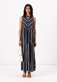 Vestido maxi listrado azul marinho com um design sem mangas, frente com botões e gola ajustável com laço. Apresenta uma saia em camadas e tecido leve.