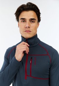 Dunkelgrauer Viertelreißverschluss-Pullover aus strukturiertem Stoff. Verfügt über rote Nähte und eine mit Reißverschluss versehenen Brusttasche mit Logo.