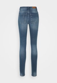 Jeans ajustados de mezclilla azul medio, con cintura alta, diseño de cinco bolsillos, ligeros desgastes en los bolsillos traseros y una textura suave.