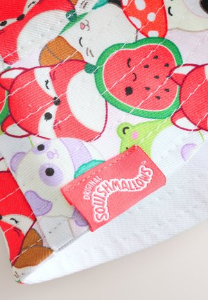 Šareni pamučni materijal s uzorcima crtane životinje i voća. Sadrži crvenu oznaku na kojoj je bijelim slovima ispisano "Original Squishmallows".