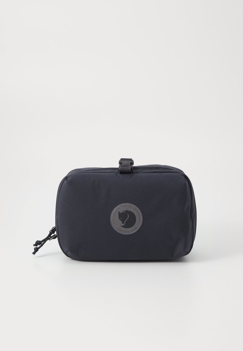 Navy blue travel pouch made of durable fabric, featuring a round logo patch, zip closure, and a textured surface with pull tab accents.