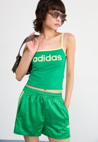 Green cotton tank top with yellow accents and "adidas" logo, paired with green pinstripe shorts and brown sunglasses.