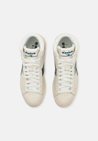 Sneakers alte in pelle crema con accenti verdi, dotate di lacci bianchi, punta perforata e logo sulla linguetta.