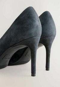 Musta mokkanahka korkokengät, joissa on terävä kärki ja stiletto-korko. Pinnassa on pehmeä rakenne, ja korko on noin 10 cm korkea.