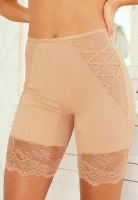 Huide shorts met kantaccenten. Glad materiaal met een lengte tot halverwege de dijen, met bloemenkant aan de rand en een kruislings ontwerp aan de zijkant.