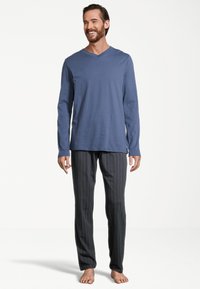 Herren-Loungewear-Set mit einem langärmligen, blauen V-Ausschnitt-Oberteil und schwarzen gestreiften Hosen, aus weichem Stoff mit lockerer Passform.