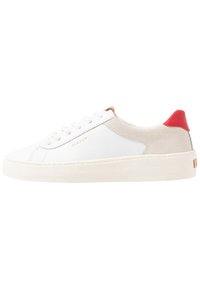 White leather sneaker with beige suede accents and a red heel tab. Features a textured sole and gold branding on the side.