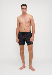 Pantaloni scurți de înot negri cu lettering roșu "MOSC", talie cu șnur și croială confortabilă. Textură fină, design până la genunchi.