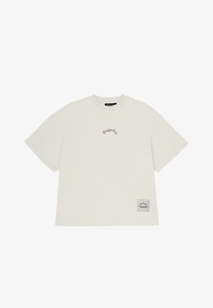 T-shirt oversize grigio chiaro in cotone con maniche corte. Presenta un discreto testo "Pegador" e un'etichetta a patch sull'orlo.