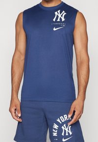 Maglietta atletica senza maniche di colore blu navy con logo bianco dei New York Yankees e swoosh Nike, realizzata in tessuto liscio e dalla vestibilità comoda.