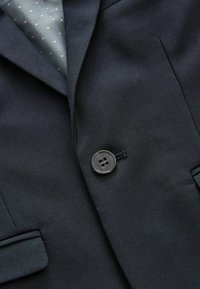 Blazer blu scuro con rever a taglio, chiusura con un bottone nero e una finitura in tessuto liscia con una leggera lucentezza.