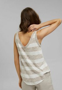 Top de tirantes a rayas con un diseño de espalda en V, confeccionado en una tela ligera y texturada en tonos neutros de beige y crema.