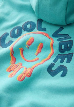 Tyrkysový mikin s kapucňou so grafickým potlačou usmievajúcej sa tváre a frázou "COOL VIBES" tučnými písmenami.
