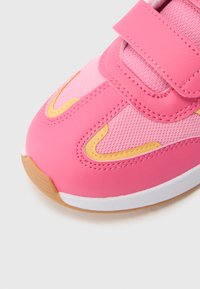 Rausvos spalvos sportbačiai su tinklelio ir sintetiniu viršumi, pabrėžti geltonais akcentais ir su lipniu dirželiu. Apvalūs pirštai ir tekstūruota guminė pado dalis.