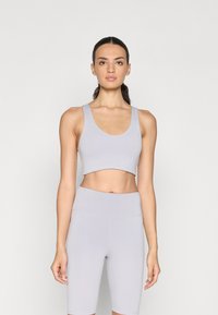 Crop top deportivo gris claro y pantalones cortos de tiro alto, con una textura suave y costuras mínimas, adecuados para ropa de deporte.