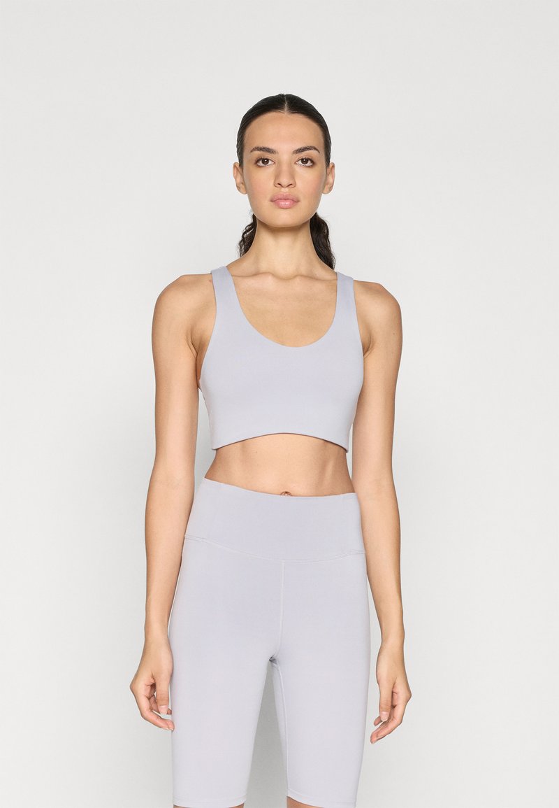 Crop top deportivo gris claro y pantalones cortos de tiro alto, con una textura suave y costuras mínimas, adecuados para ropa de deporte.